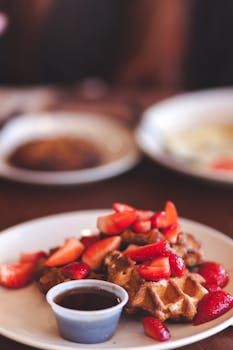 Indulge in delicious waffles topped with fresh strawberries and syrup.