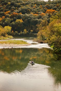 A kayaker enjoys a peaceful paddle on a scenic river surrounded by vibrant fall foliage.