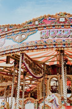 Vibrant and colorful carousel at an amusement park under a clear blue sky.