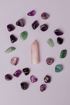 Flat lay of assorted gemstones and rose quartz on a purple background.