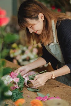 Asian woman florist happily arranges flowers in a vibrant workshop setting.