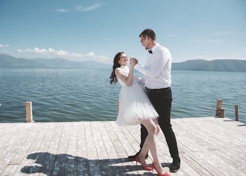A couple joyfully dances on a dock by Lake Oteshevo, embracing love under a sunny sky.