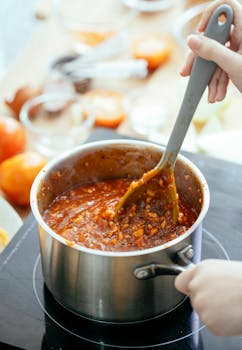 A person stirring a pot of homemade chili stew on a stovetop, capturing the essence of home cooking.