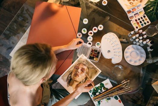 High angle view of a woman painting a portrait using watercolors inside a studio.